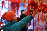 Un enfant tend le bras vers une peluche représentant le tigre du zodiaque chinois