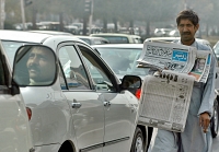 Un vendeur de rue tient le journal présentant le tirage des Prize Bonds à Islamabad