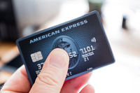 Une main tient une carte de credit America Express (Amex)